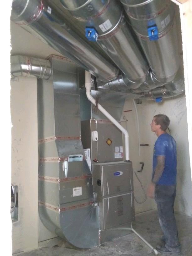 An HVAC technician standing next to a newly installed furnace and extensive ductwork by Element Heating & Cooling, Inc. in Twin Falls, ID