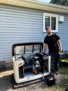 A friendly Kelley Brothers LC technician standing next to an open Generac standby generator after service in Livonia, MI.