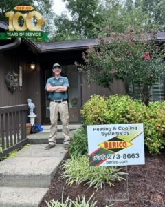 A Berico HVAC technician standing proudly next to a "Heating & Cooling Systems" sign in Greensboro, NC