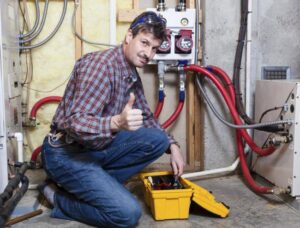 An HVAC technician giving a thumbs up next to a hydronic heating system with red pipes at Berkeley Heating and Air Conditioning in Hanahan, SC