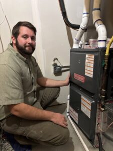 An HVAC technician kneeling next to an indoor furnace after service by Polar Air Heating and Cooling in Omaha, NE