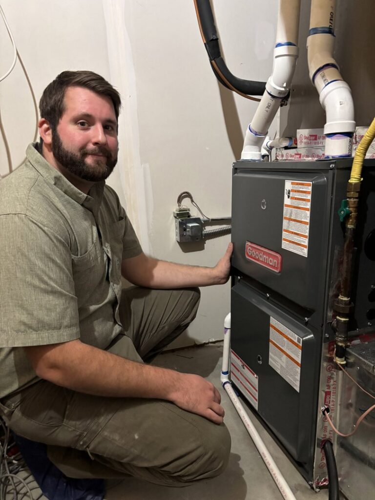 An HVAC technician kneeling next to an indoor furnace after service by Polar Air Heating and Cooling in Omaha, NE