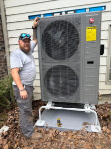 An HVAC technician standing proudly next to a newly installed outdoor heat pump unit for Empire Heating & Air Conditioning in Decatur, GA