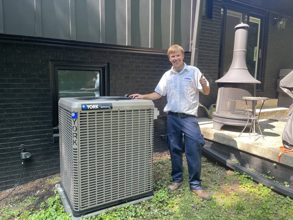 An HVAC technician giving a thumbs up next to a newly installed YORK AC unit by Delta Heating, Cooling, Plumbing in Wilson, NC.