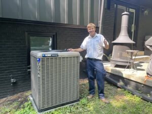 An HVAC technician giving a thumbs up next to a newly installed YORK AC unit by Delta Heating, Cooling, Plumbing in Wilson, NC.