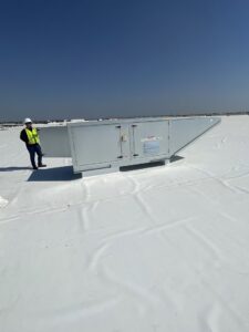 An HVAC technician inspecting a large commercial rooftop unit for Norway Air Conditioning Inc. in Laredo, TX.