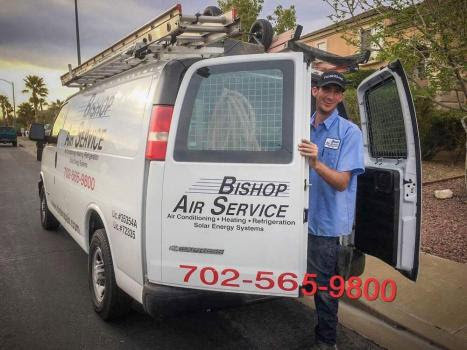 An HVAC technician from Bishop Air Service smiling next to a branded service van in Henderson, NV.