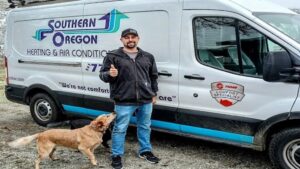 An HVAC technician giving a thumbs-up next to a branded service van from Southern Oregon Heating & Air Conditioning in Medford, OR