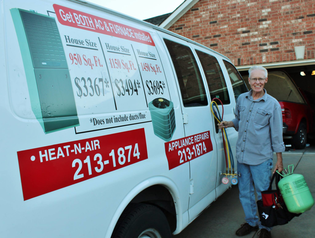 An HVAC technician holding gauges and a refrigerant tank next to a service van for West Wichita Heating & Air Conditioning in Wichita, KS.