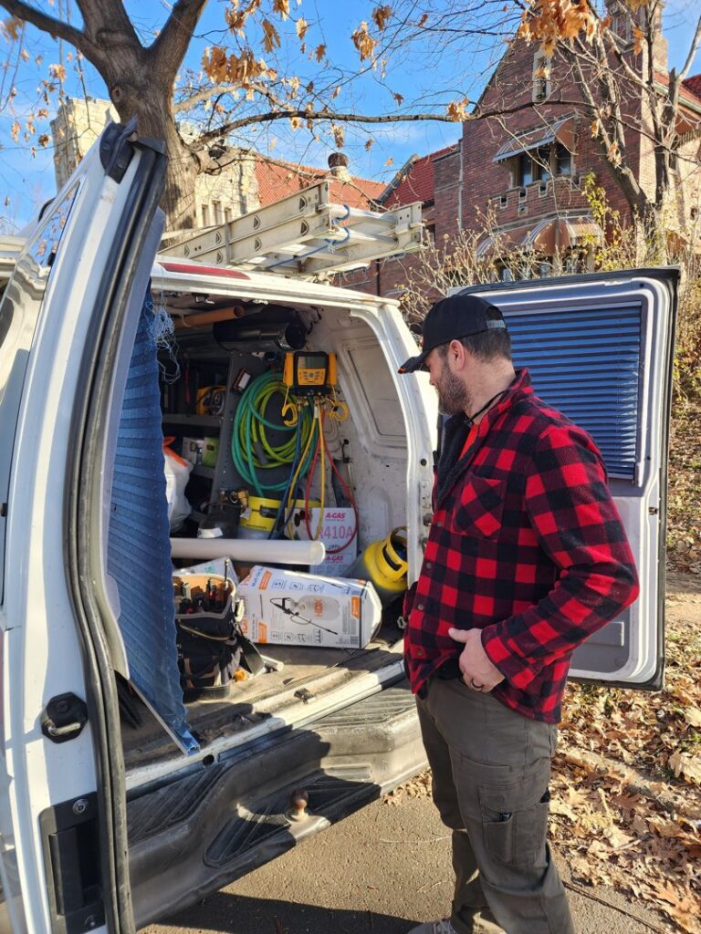 An HVAC technician standing by a work van filled with tools and equipment on a job site for Dad's Heating and Cooling in Blue Springs, MO.
