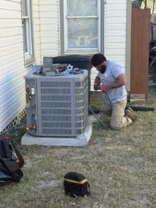 An HVAC technician from Gibson's Air Conditioning & Heating working on an outdoor AC condenser unit in Corpus Christi, TX.