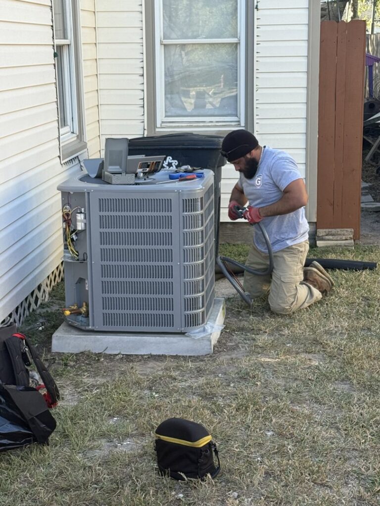 An HVAC technician from Gibson's Air Conditioning & Heating working on an outdoor AC condenser unit in Corpus Christi, TX.