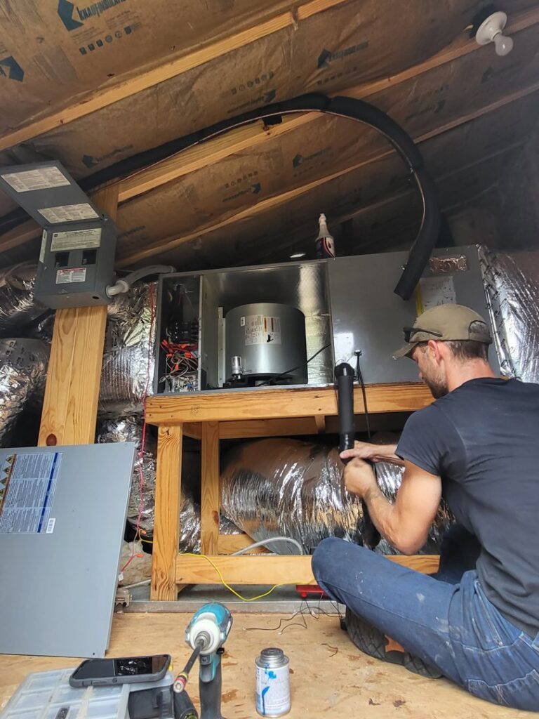 An HVAC technician performing service on an indoor air handler unit in an attic for Gouker's Best Air in Franklin, TN.