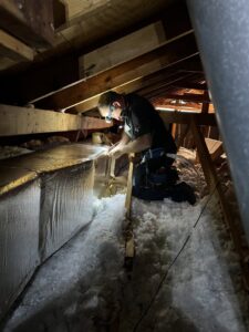An HVAC technician working on ductwork in an attic for Fields Cooling Heating & Refrigeration in Foley, AL.