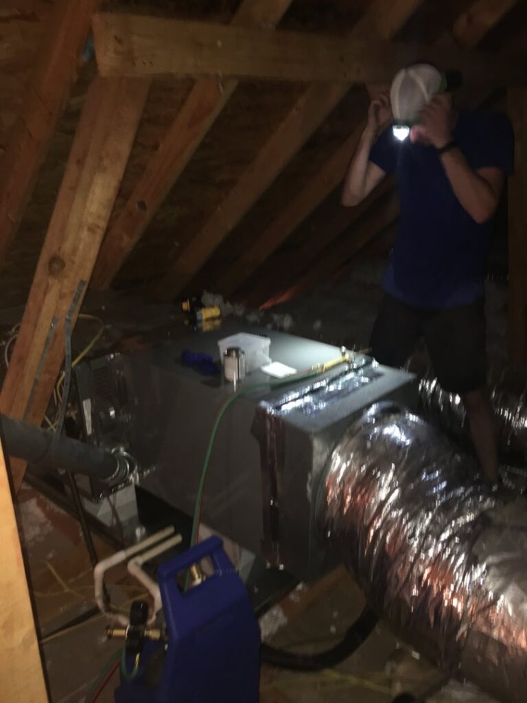 An HVAC technician working on an air handler unit in an attic for Controlled Climate Solutions in Decatur, AL.