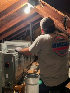 An HVAC technician from Johnson's A/C & Heating working on an indoor unit in an attic in Alexandria, LA.