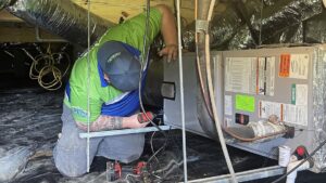 An HVAC technician from Top Notch Heating and Air Conditioning working on an indoor unit in a crawl space in Bowling Green, KY.