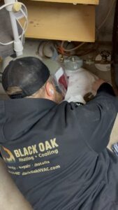 An HVAC technician from Black Oak HVAC working on a gas line connection in Derry, NH