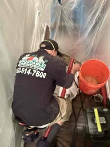 An HVAC technician from Affordable Heating and Air working in a confined attic space in Chatsworth, CA.