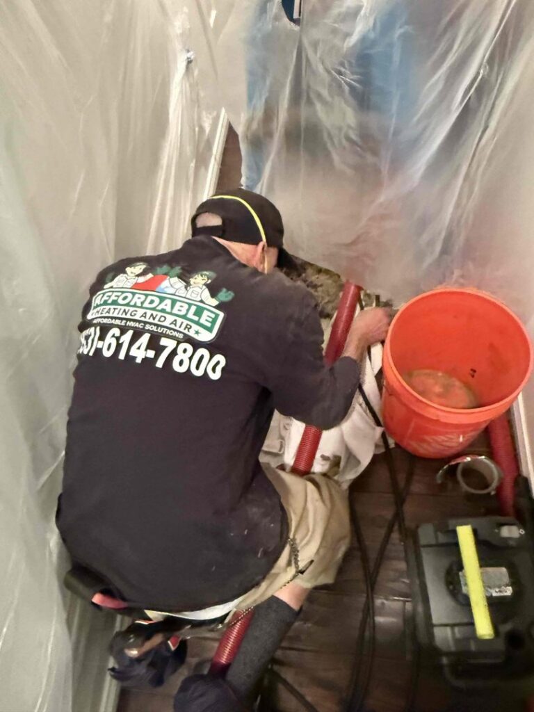 An HVAC technician from Affordable Heating and Air working in a confined attic space in Chatsworth, CA.