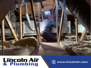 A Lincoln Air & Plumbing technician working on an HVAC unit and ductwork in an attic in Phoenix, AZ