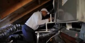An HVAC technician working on an air handler unit in an attic for Metro Air Conditioning, Heating & Services in Dallas, TX