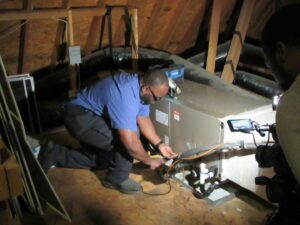 An HVAC technician working on an indoor air handler unit in an attic for On Call Plumbing, Heating & Air in Columbia, SC