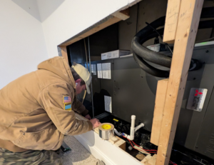 An HVAC technician working on an indoor air handler unit for Frontier 44 Corp. in Melrose, MA.