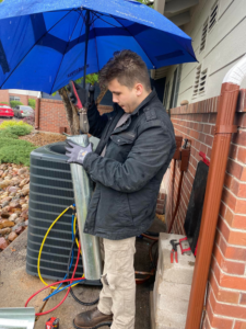 An HVAC technician working on an outdoor AC unit and ductwork for 5280 Cooling Heating & Refrigeration in Lakewood, CO