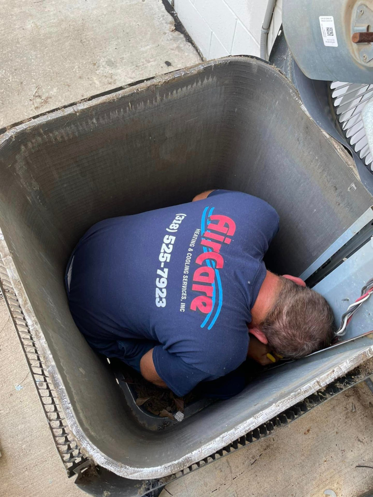 An Air Care Heating and Cooling Services technician working inside an outdoor AC unit in Shreveport, LA.
