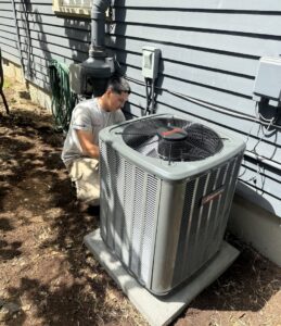 An HVAC technician from JCL Heating and Cooling LLC working on an outdoor AC unit in Gresham, OR.