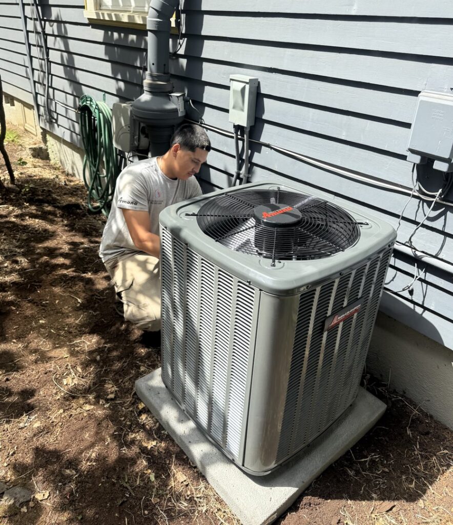 An HVAC technician from JCL Heating and Cooling LLC working on an outdoor AC unit in Gresham, OR.