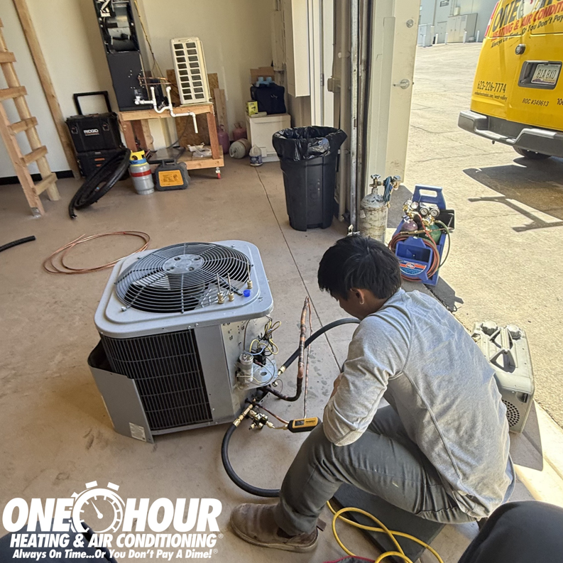 An HVAC technician working on an outdoor AC unit at One Hour Heating & Air Conditioning of West Valley in Phoenix, AZ