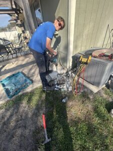 An HVAC technician working on an outdoor AC unit pad with tools, performing service for Whitleys Heating and Air in Jacksonville, FL.