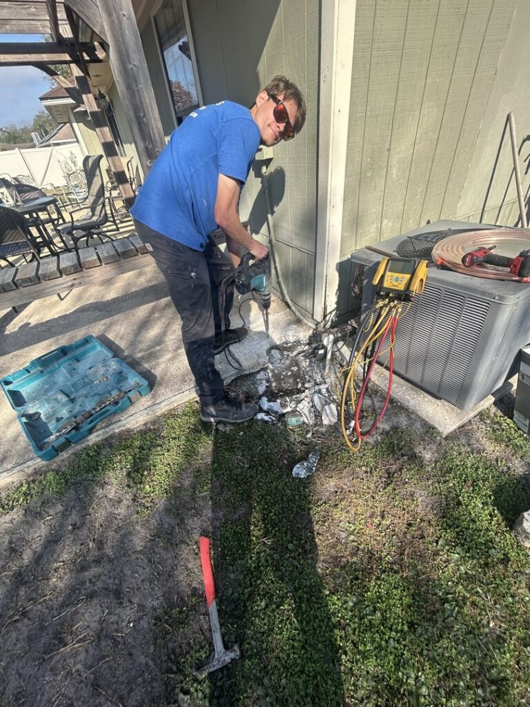 An HVAC technician working on an outdoor AC unit pad with tools, performing service for Whitleys Heating and Air in Jacksonville, FL.