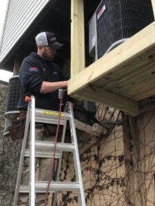 An HVAC technician from Wight's Heating & Air Conditioning working on an outdoor AC unit in Rockford, IL