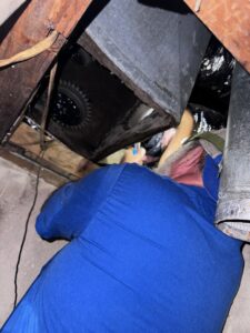 An ARKLA AIR LLC technician working on ductwork in a tight attic space, performing an HVAC repair or installation in Springhill, LA.
