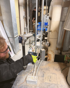 An HVAC technician performing work on boiler pipes and controls in a utility room for Climate Systems, Inc. in Sioux Falls, SD.