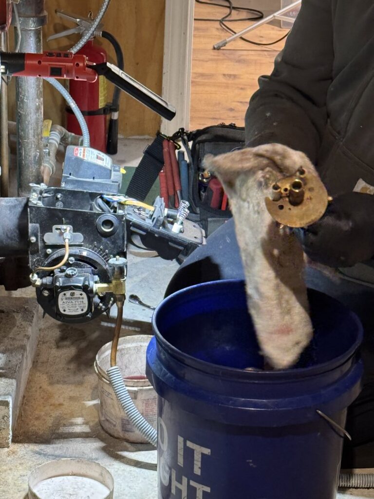 An HVAC technician working on an oil burner component for Aaron Hamilton Heating in Brunswick, ME.