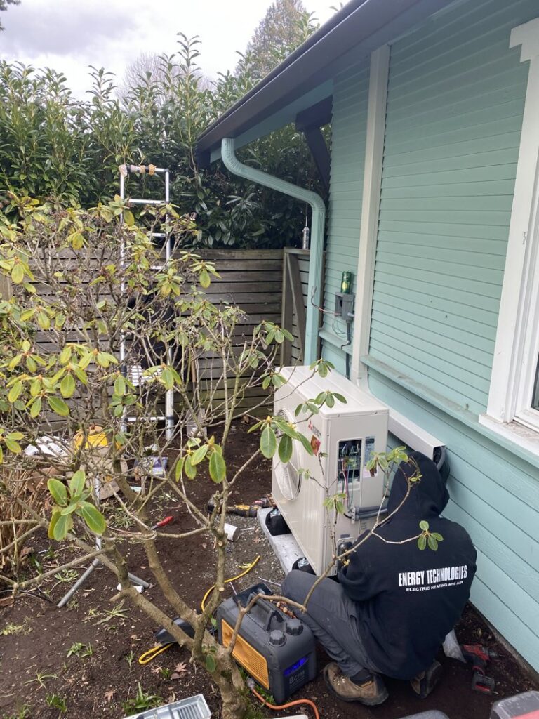 An HVAC technician from Energy Technologies working on an outdoor condenser unit in Seattle, WA.