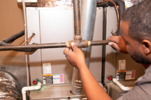 An HVAC technician from Nashville Solutions working on copper piping connected to an indoor unit in Nashville, TN