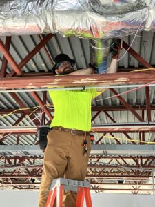 An HVAC technician working on a duct system in a commercial building for Blue Fox Heating & Cooling in Lebanon, IN.