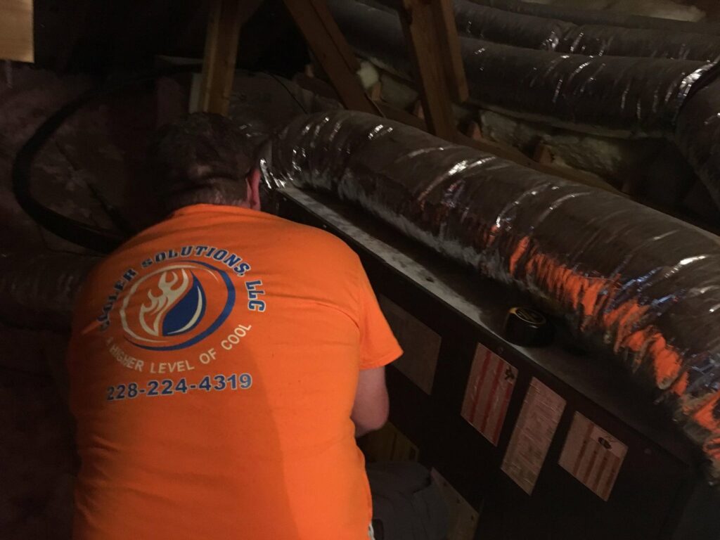 An HVAC technician working on ductwork and an air handler in an attic for Cooler Solutions LLC Heating & Air in Gulfport, MS.
