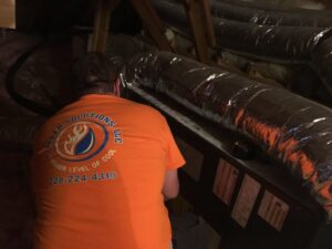 An HVAC technician working on ductwork and an air handler in an attic for Cooler Solutions LLC Heating & Air in Gulfport, MS.