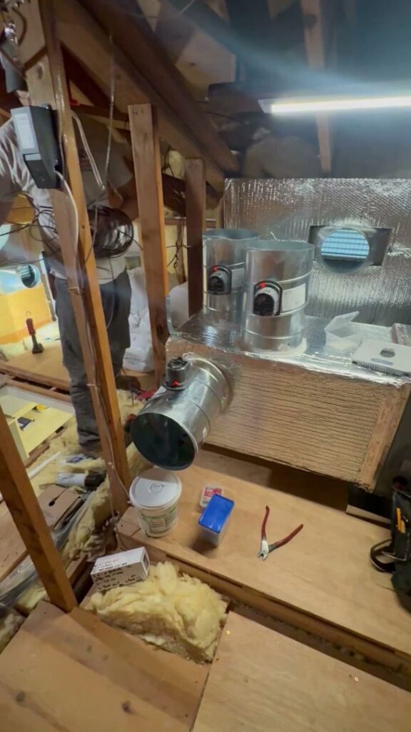 An HVAC technician working on ductwork and components in an attic for Pelican Heating and Air in Carlsbad, CA.