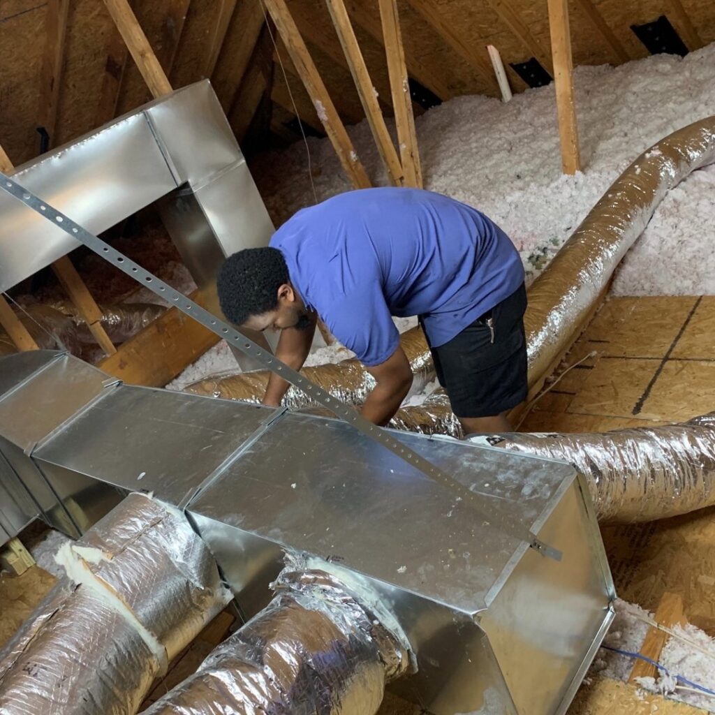 An HVAC technician installing or repairing ductwork in an attic for Ward Mechanical Contractors in Denham Springs, LA.