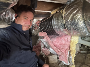 An HVAC technician working on insulated ductwork in a crawl space for Eaton Companies LLC in Clarksville, TN.