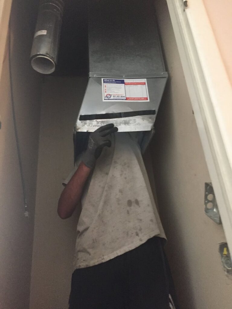 An HVAC technician working on ductwork during a service call by ICare Heating & Air in Millcreek, UT.