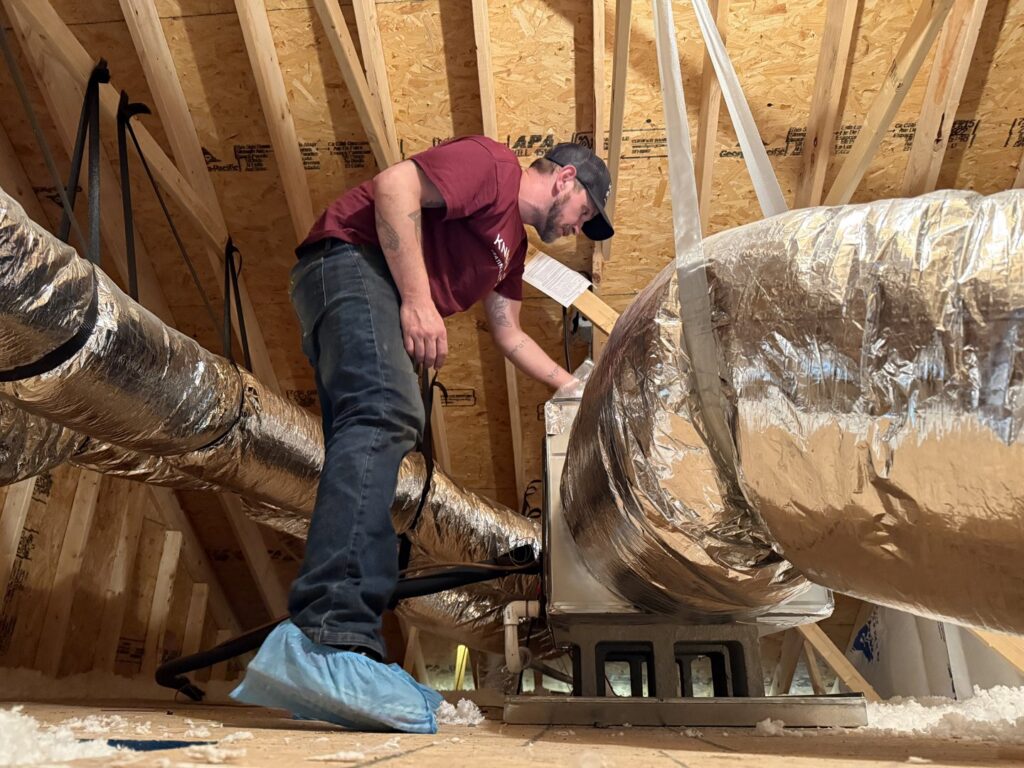 An HVAC technician working on ductwork and an air handler in an attic space for Know A Guy Heating & Air Conditioning in Kernersville, NC.