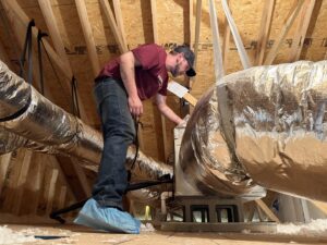 An HVAC technician working on ductwork and an air handler in an attic space for Know A Guy Heating & Air Conditioning in Kernersville, NC.